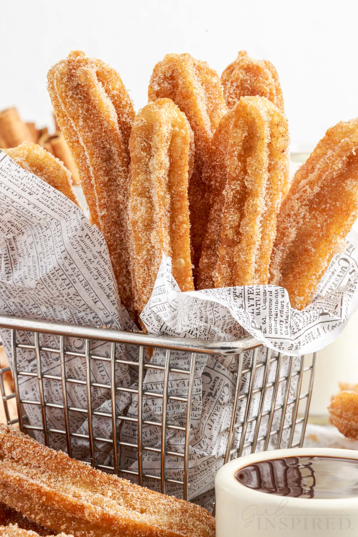 Front close up of Churros in a lined metal basket.