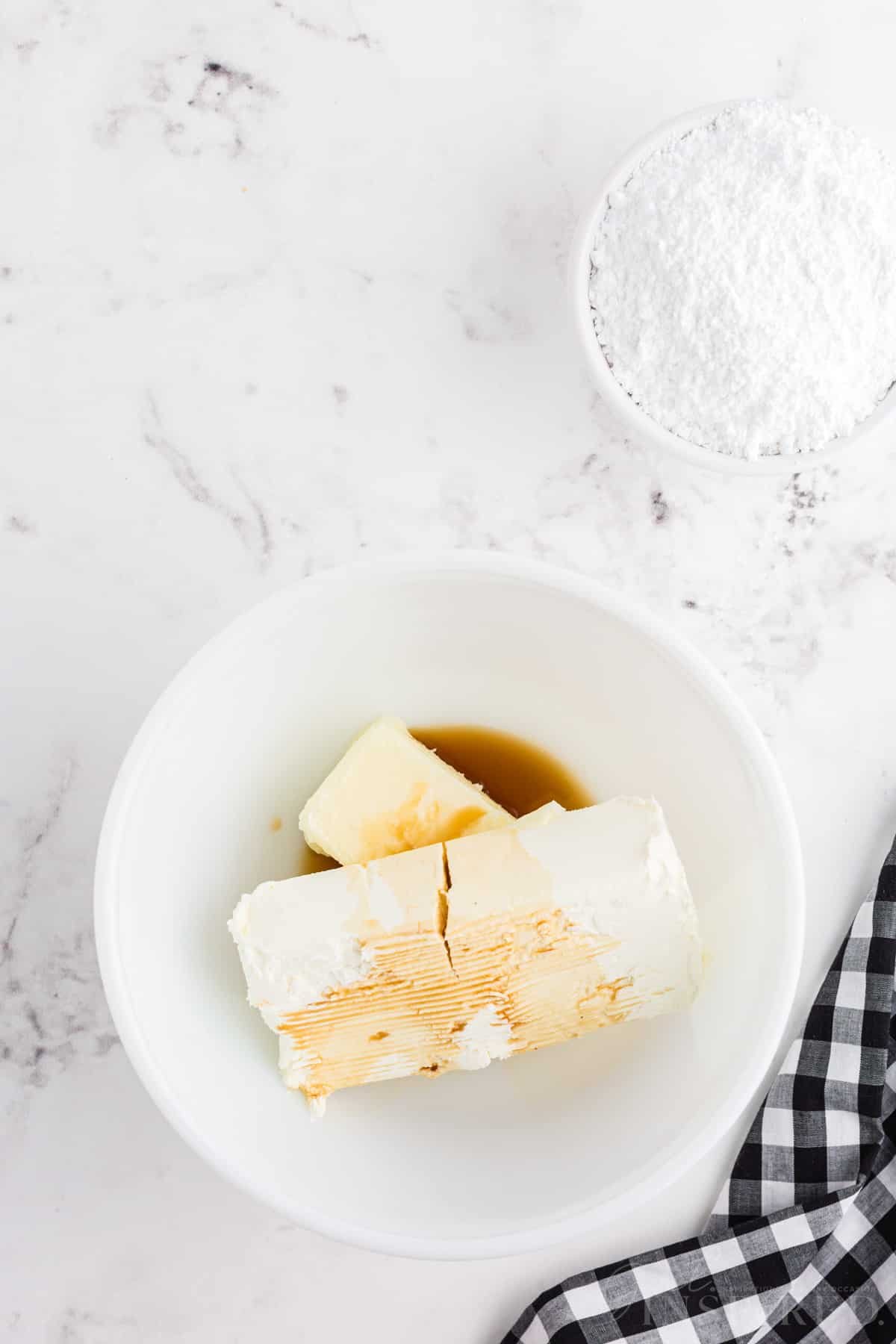 Mixing bowl with softened butter, cream cheese, and vanilla extract.