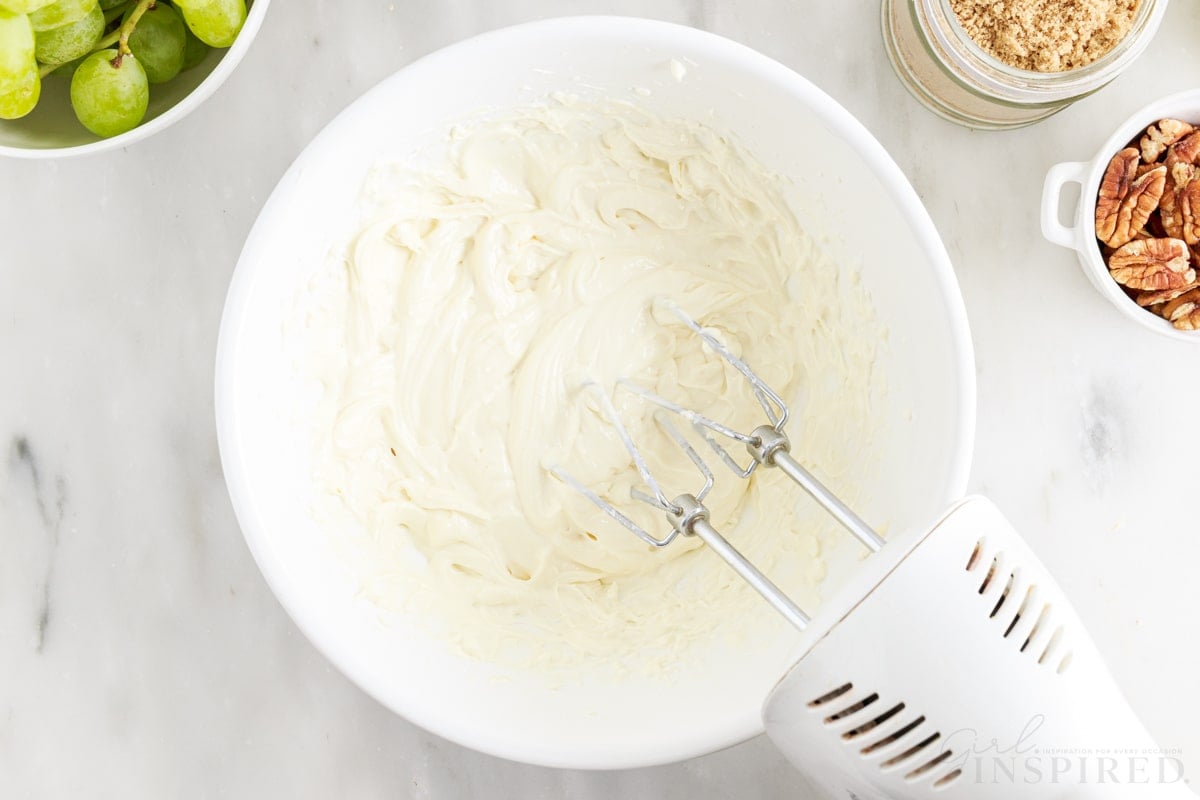 Electric mixer beating cream cheese mixture for the grape salad dressing.
