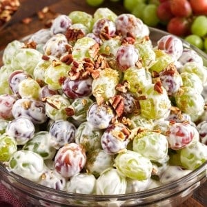 Side view of creamy grape salad mounded in glass serving bowl.