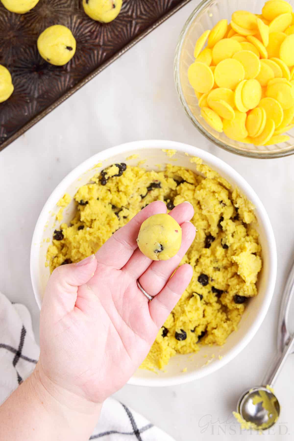 Ball of lemon blueberry cheesecake mixture in palm of hand.