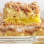Close-up of a slice of lemon coffee cake suspended on a fork above the remaining cake.
