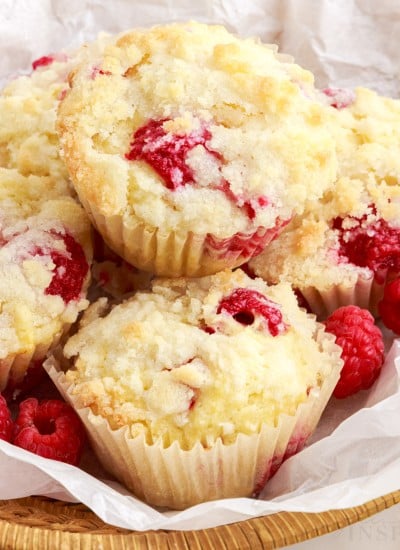 Lemon Raspberry Muffins in a lined basket with raspberries.