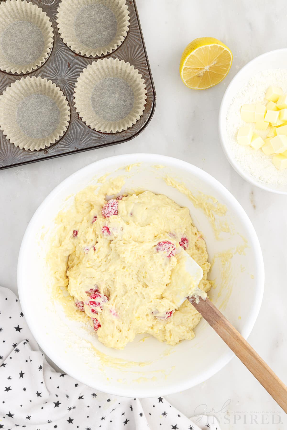 Raspberries stirred into the batter with a spatula inserted.