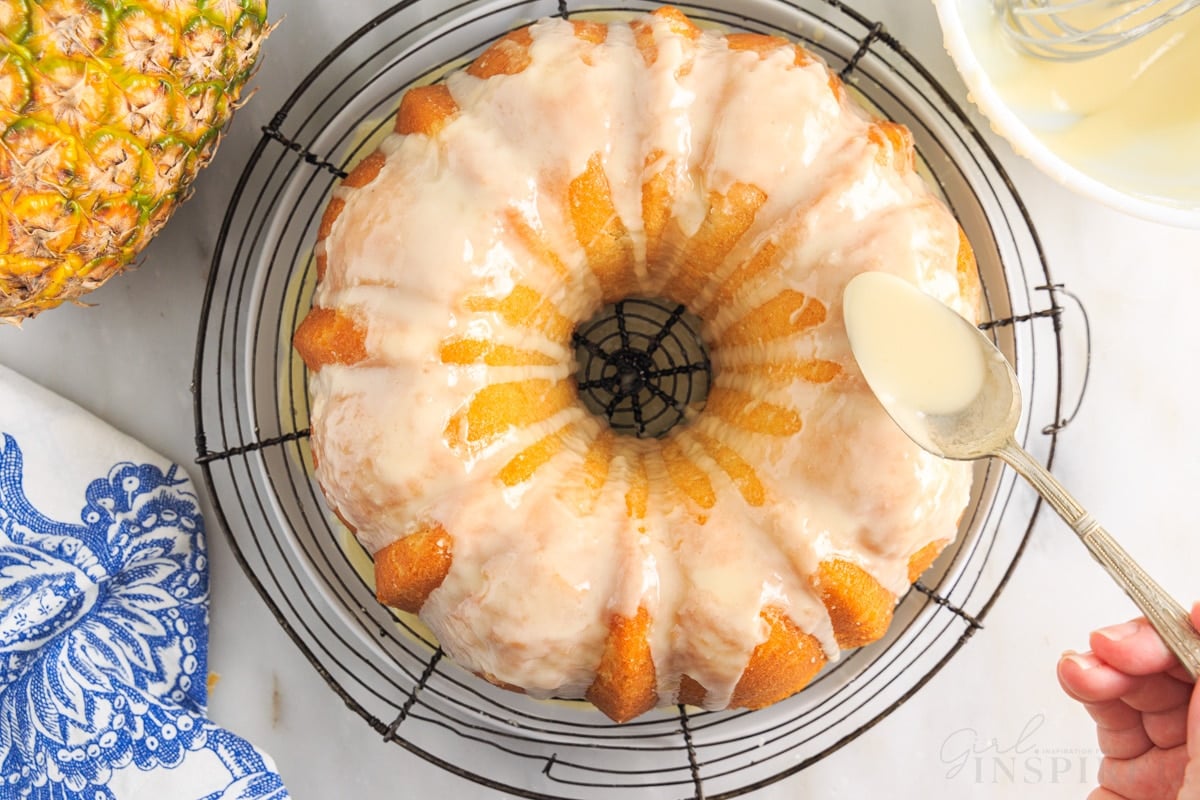 Glaze drizzled over Pineapple Pound Cake on a cooling rack with a spoon.