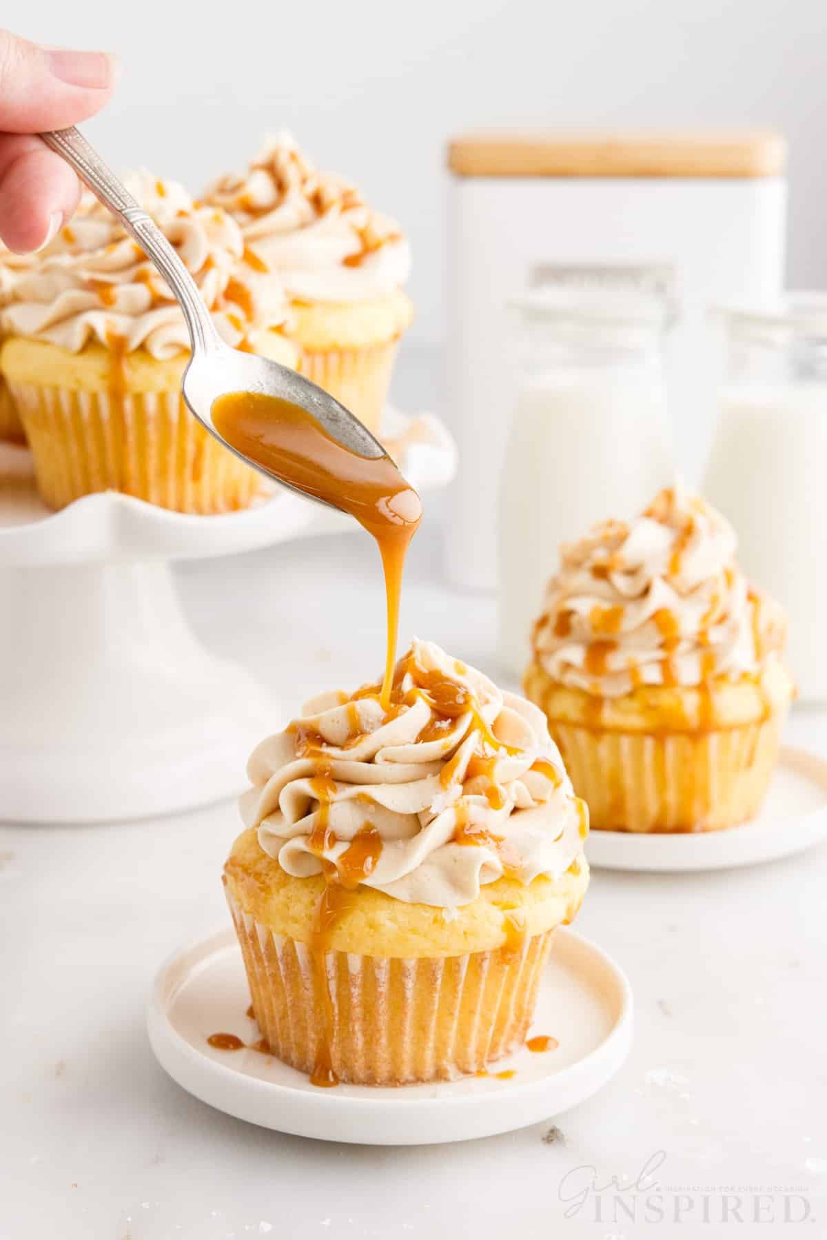 Caramel being drizzled from a spoon onto a Salted Caramel Cupcake.