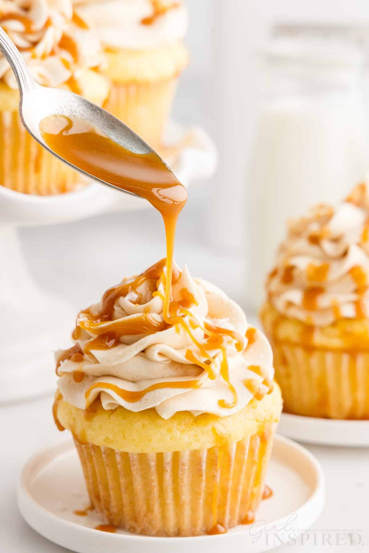 Caramel drizzled from a spoon onto a Salted Caramel Cupcake.