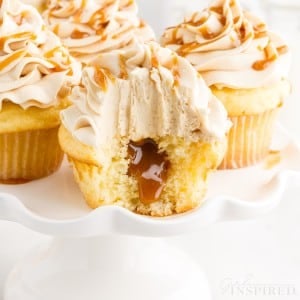 A tiered tray of Salted Caramel Cupcakes with a bite taken from the front one.