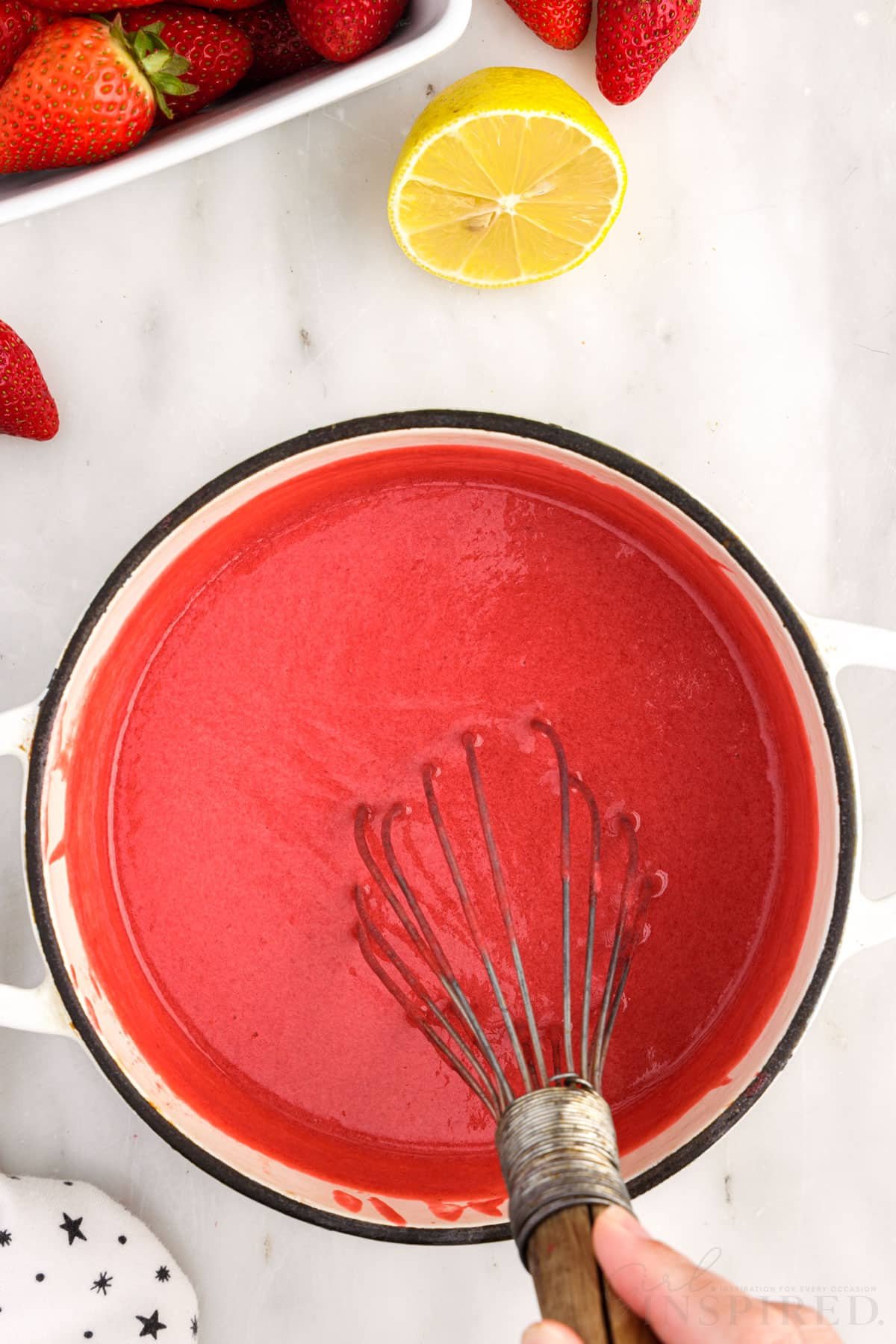 Strawberry puree stirred in a pot with a whisk.
