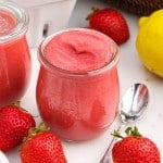 Close up of two glasses of Strawberry Curd along with strawberries lemon and a spoon.