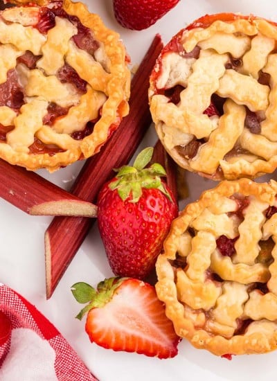 Overhead view of Strawberry Rhubarb Mini Pies with strawberries and rhubarb slices.