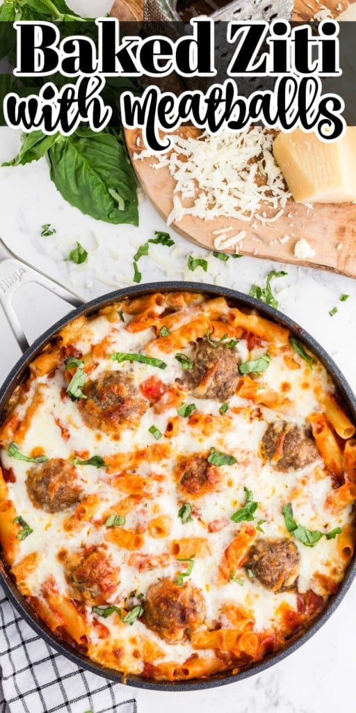Baked Ziti with Meatballs in a large skillet on a marble countertop, wooden kitchen board with grated cheese and cheese blocks.