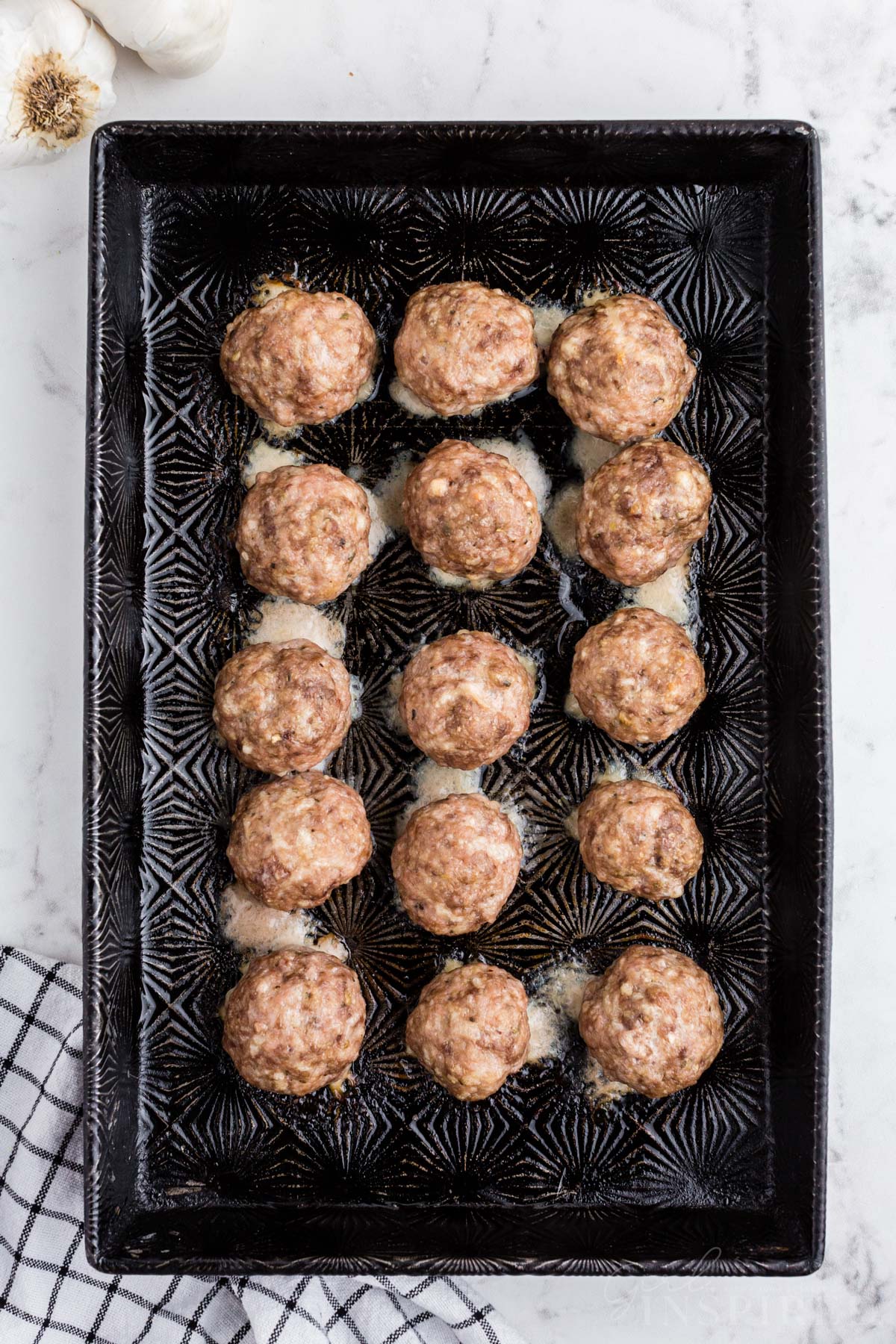 Uniform cooked meatballs on a baking tray.