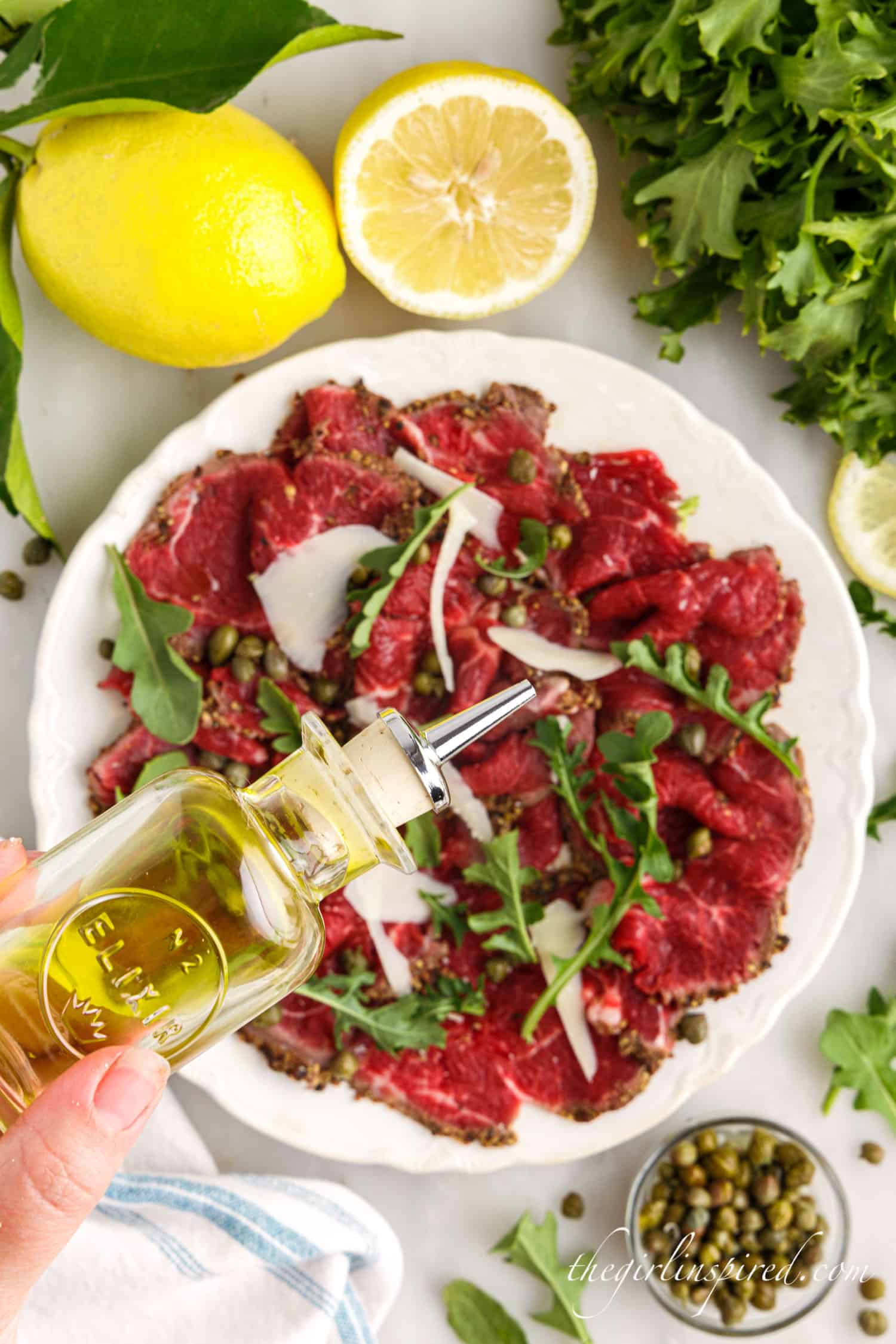 Oil drizzled over Beef Carpaccio on a plate.