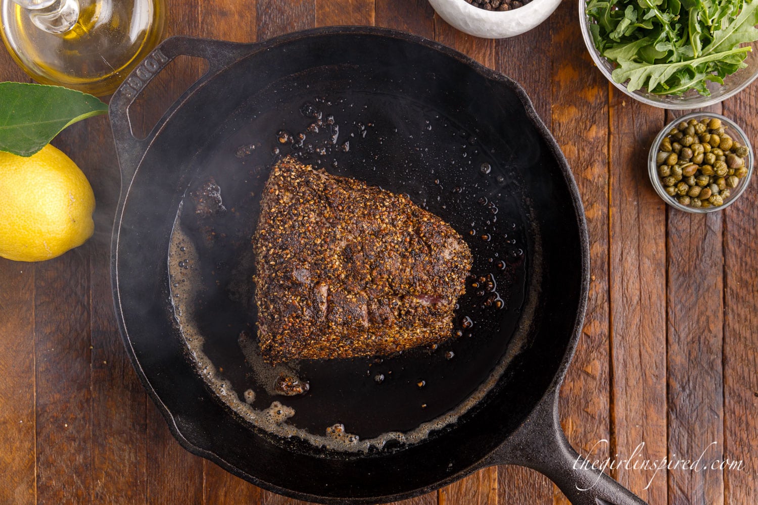 Beef tenderloin placed in cast iron skillet with melted butter.