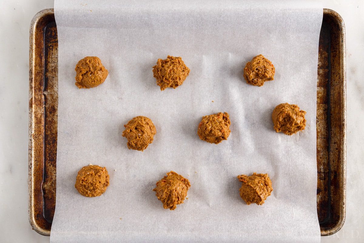 Overhead view of Carrot Cake Cookies from Cake Mix cookie dough balls on parchment paper lined cookie sheet.