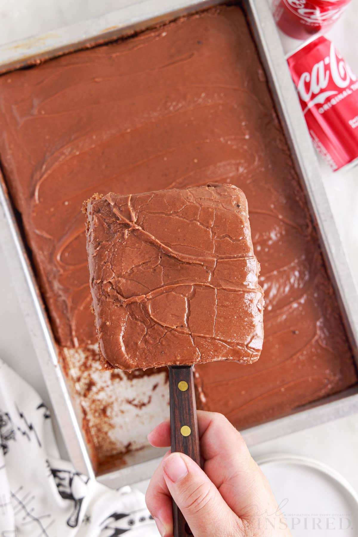 A square slice of Coca Cola Cake being lifted from the 9x13 pan.