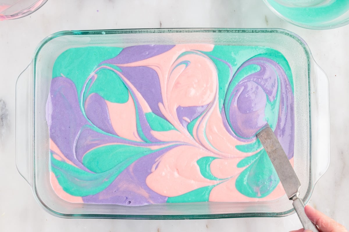 Easter Poke Cake batter swirled together with a knife in a 9x13.