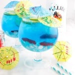 Close up of two goblets of Fish Bowl Drinks with yellow and blue drink umbrellas and Malibu in the background.