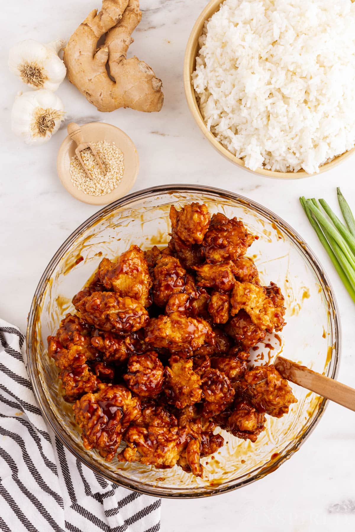 Bowl of fried chicken pieces mixed with Tso sauce, bowl of white rice.