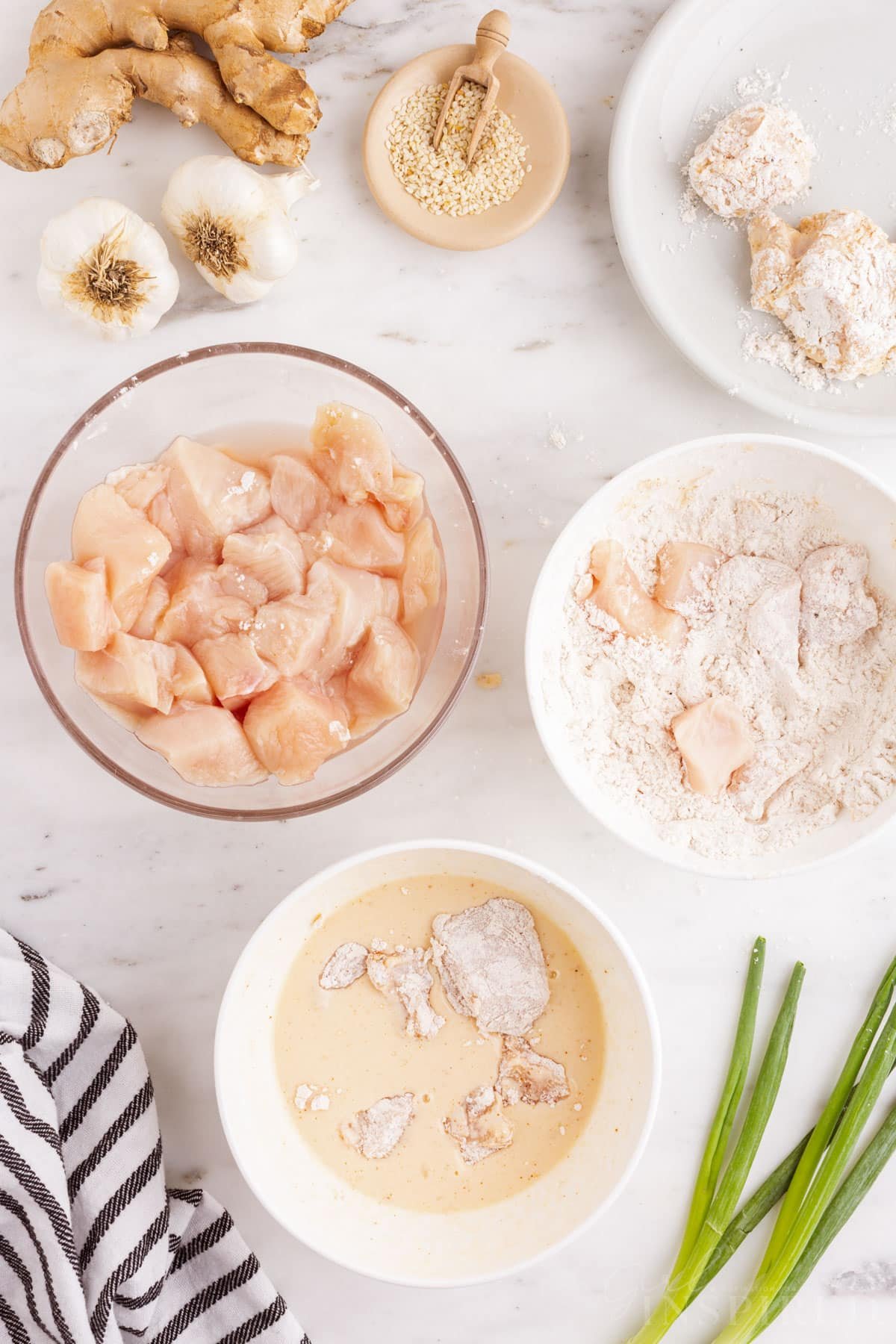 Dredging station with pieces of chicken, batter mixture, and flour.