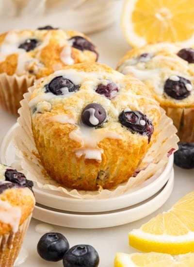 Lemon Blueberry Muffins one with the paper pulled down on two small stacked plates.