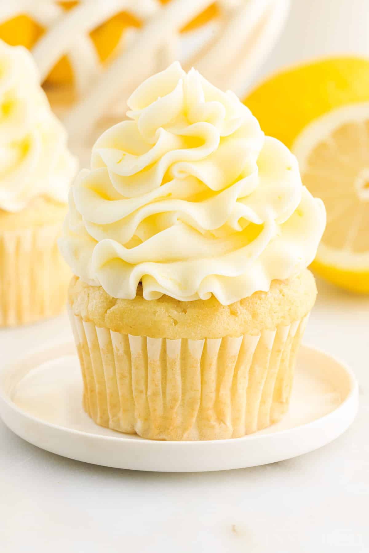 A cupcake with Lemon Buttercream Frosting on it on a small dish.