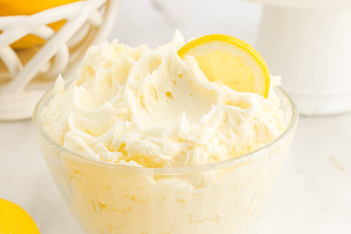 Close up of a bowl of Lemon Buttercream Frosting garnished with lemons.