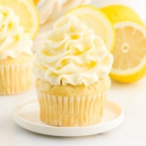 Lemon Buttercream Frosting on a cupcake with lemons in the background.