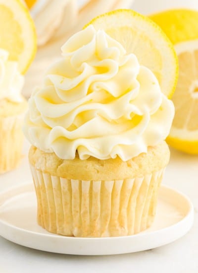 Lemon Buttercream Frosting on a cupcake with lemons in the background.