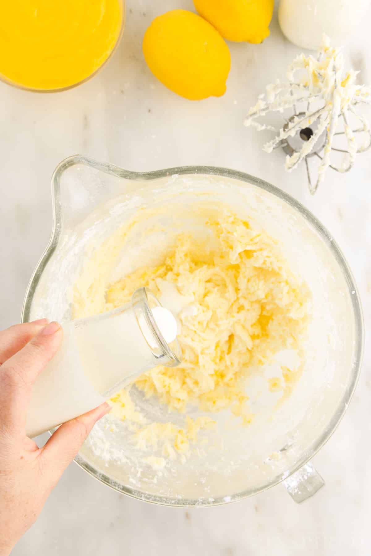 Heavy cream added to butter mixture in mixing bowl to make Lemon Buttercream Frosting.