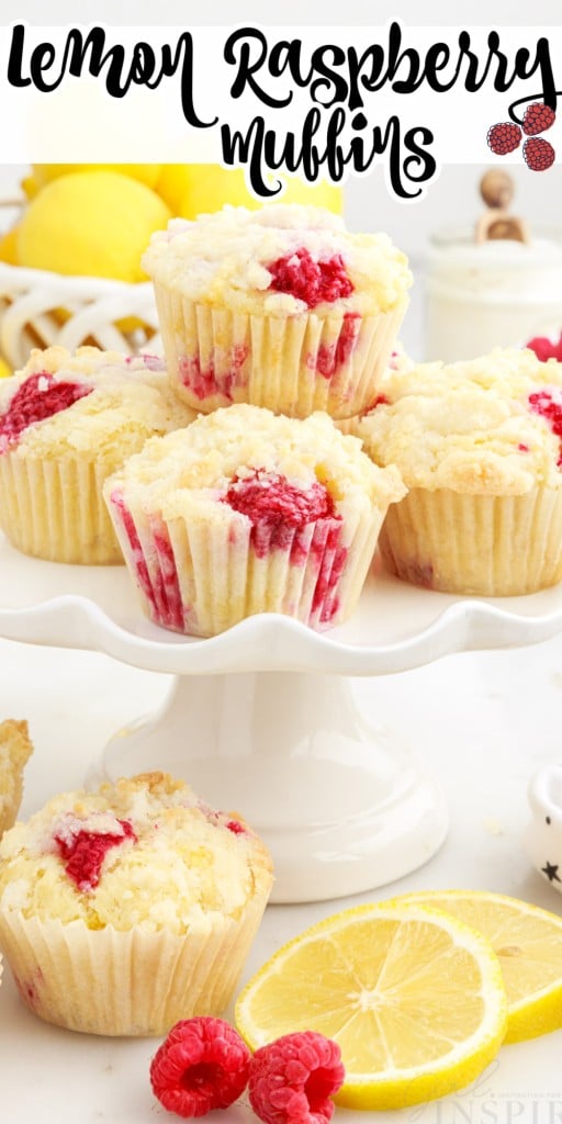 Lemon Raspberry muffins stacked on a white tiered cake stand with a basket of lemons in the background and more muffins, raspberries and lemon slices scattered in front on a white countertop