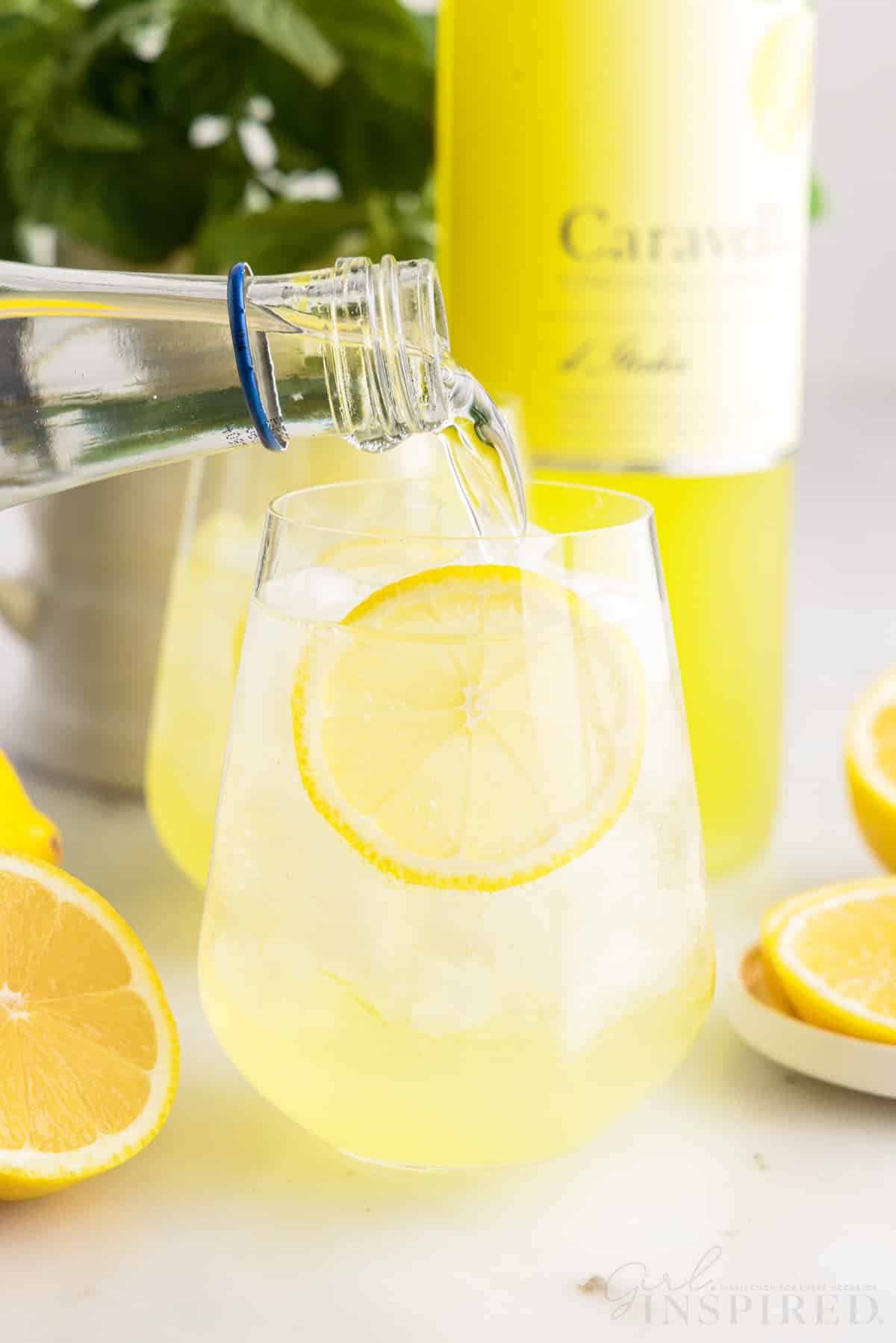 Club soda being added to glass with a bottle of Limoncello in the background.