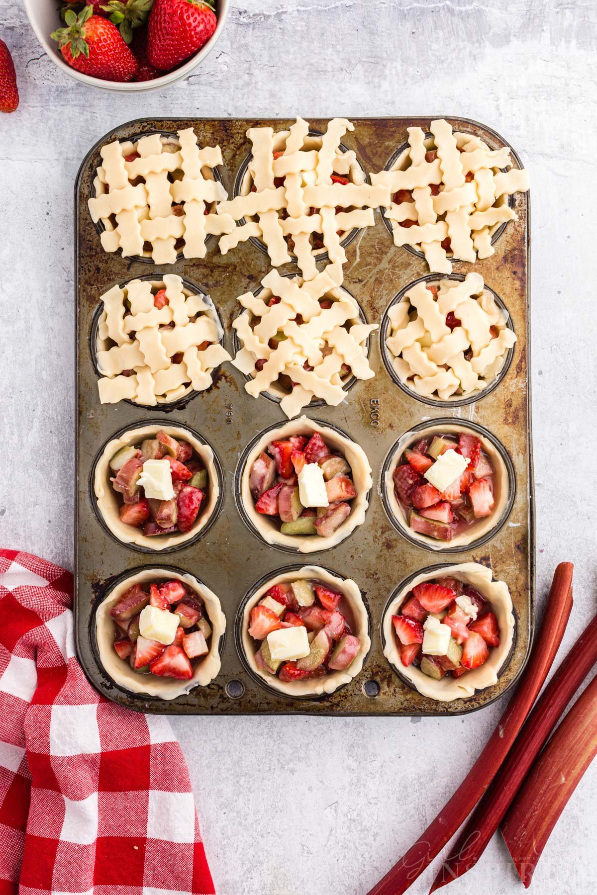 Lattice added to the top of six Strawberry Rhubarb Mini Pies in muffin tin.