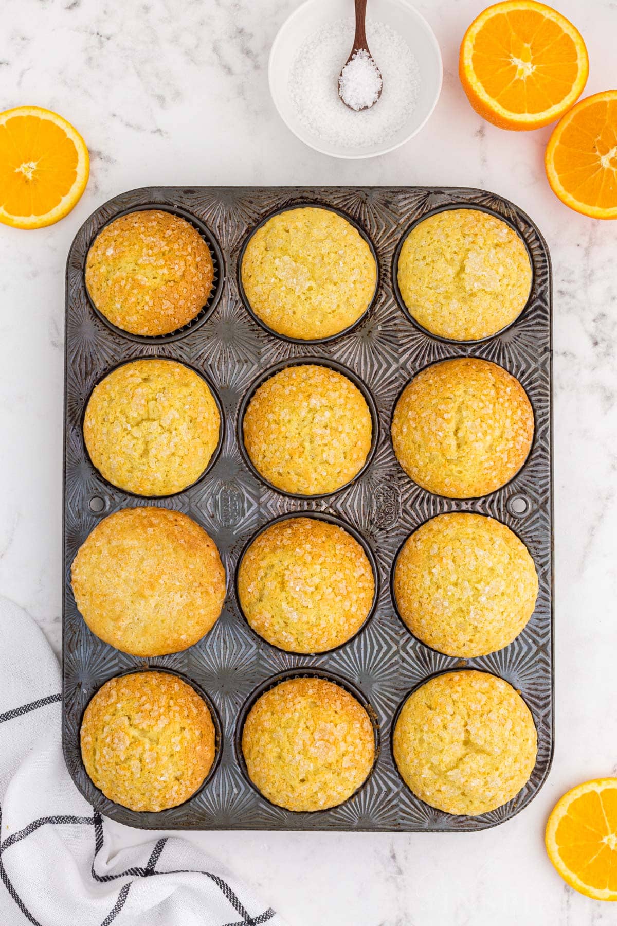Baked orange muffins in a metal muffin tin.
