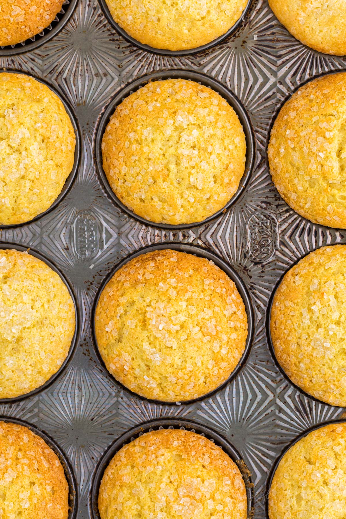 Close-up of baked orange muffins in a metal muffin tin.