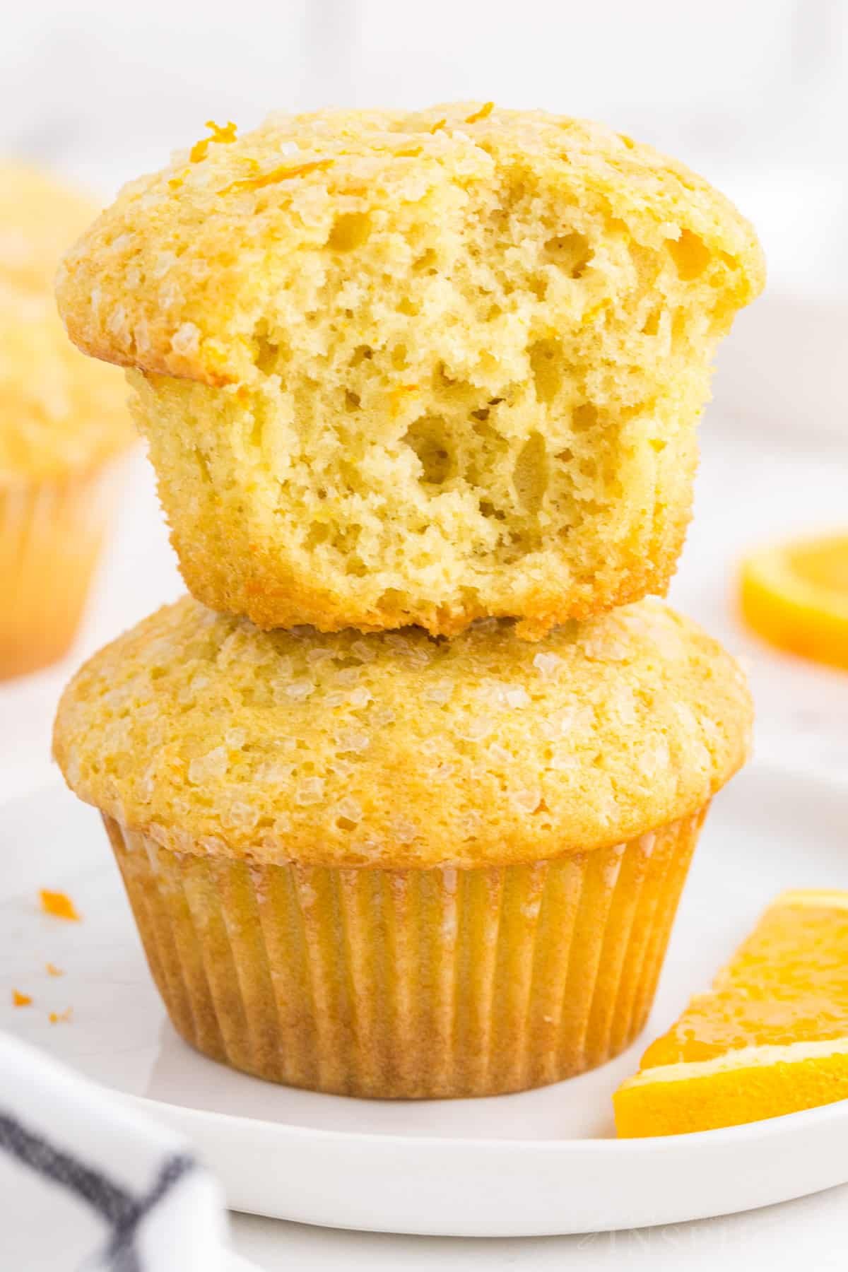 Close-up of two stacked orange muffins with a mouthful taken from the top muffin.