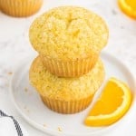 Close-up of two stacked orange muffins on a white serving plate.