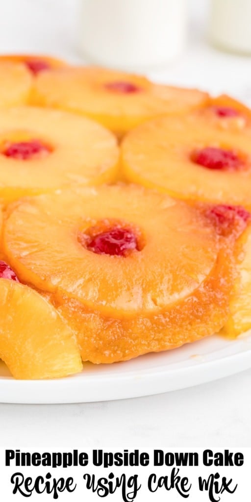 Close up of pineapple upside down cake on a white serving plate on a marble countertop.