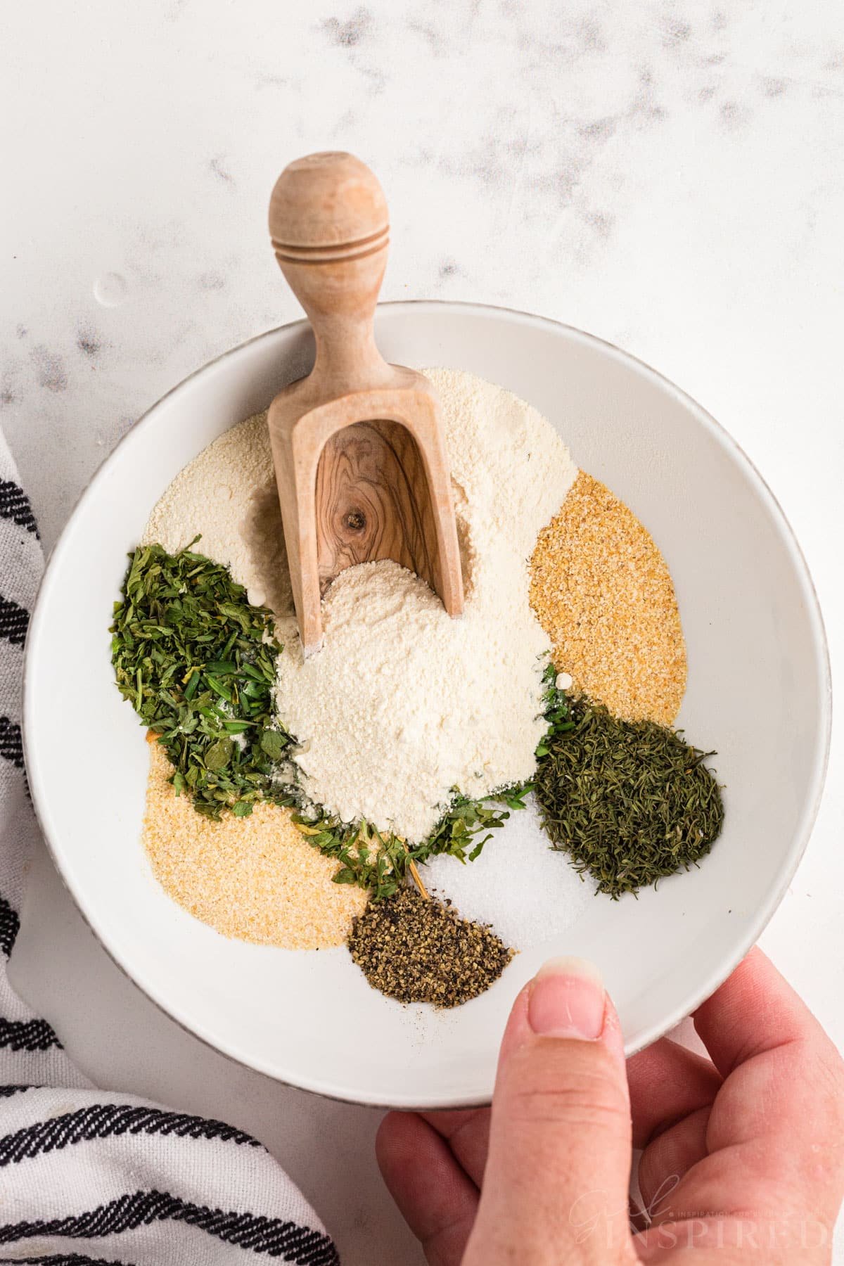 Bowl with homemade ranch seasoning ingredients; each herb and spice in its own pile.