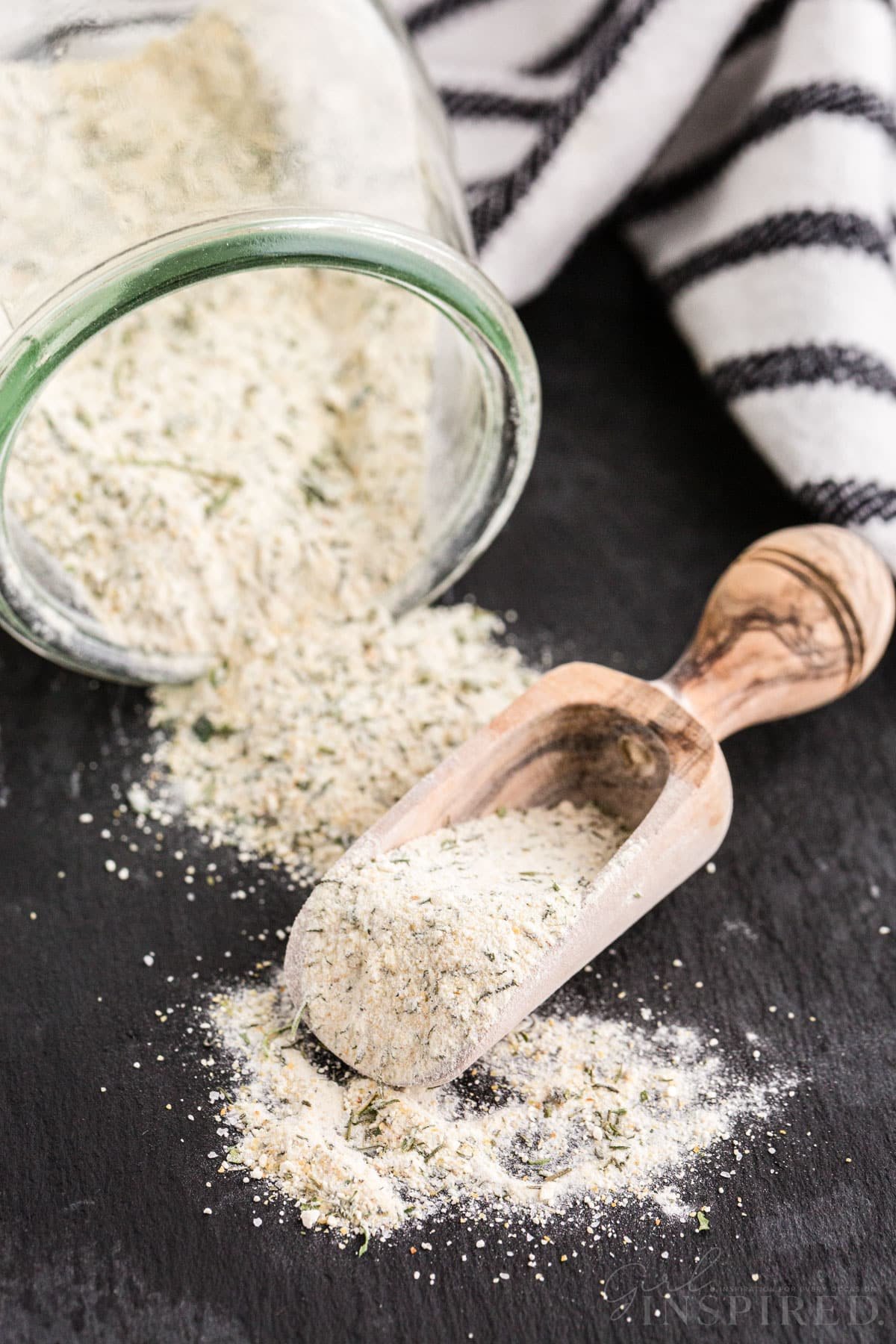 Simple ranch seasoning packet recipe in an overturned glass container, spilling onto a dark countertop.