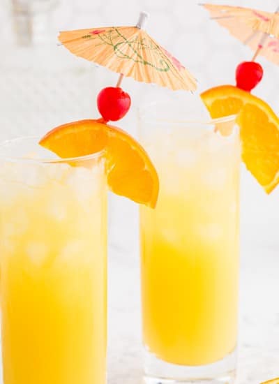 Two glasses of screwdriver drink, garnished with orange slices and cherries.
