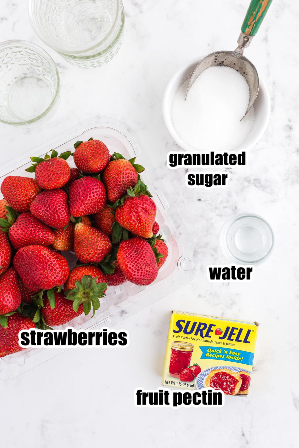 Strawberry freezer jam ingredients on a white marble countertop, with text labels.