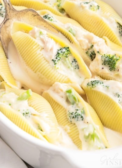 A spoon scooping a Chicken Alfredo Stuffed Shell out of a dish.