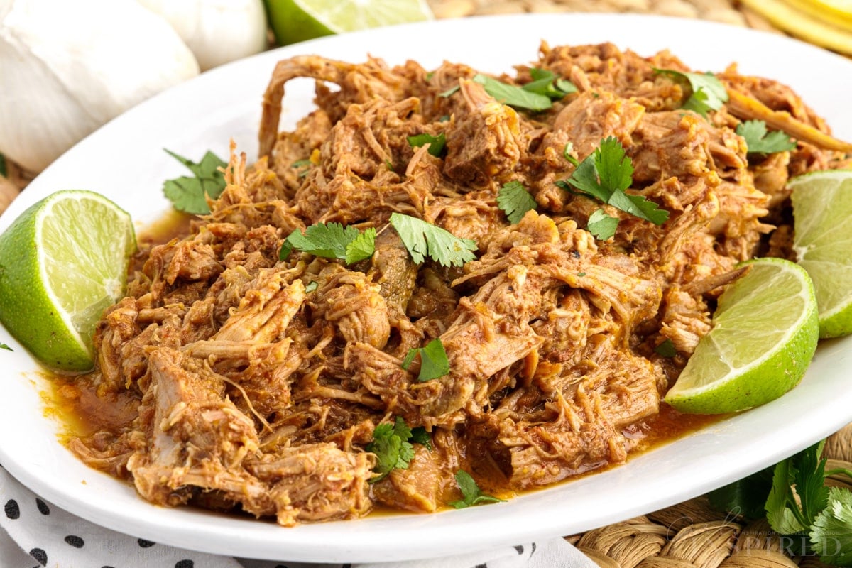 Close up of Pork Barbacoa on an oval platter with limes.