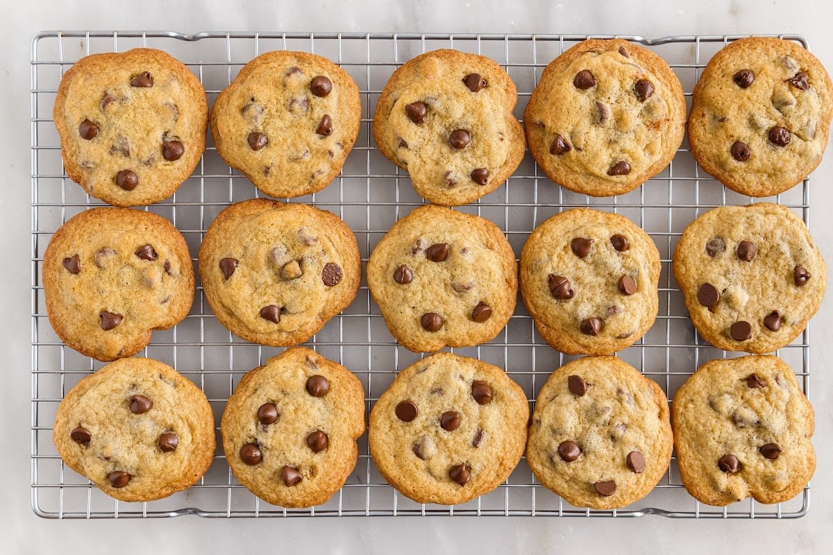Baked Toll house chocolate chip cookies lined up on a cooling rack.
