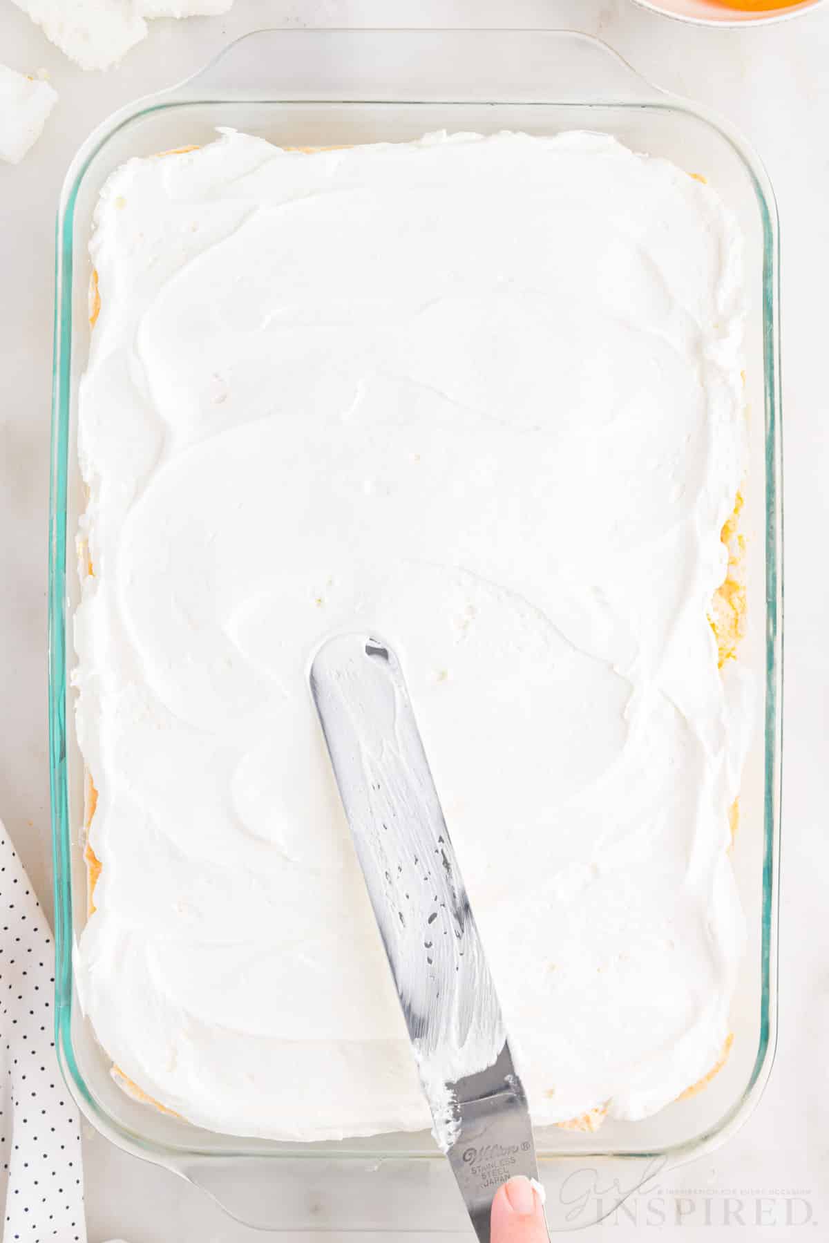 Cool whip spread out over the Apricot Delight in a 9x13.