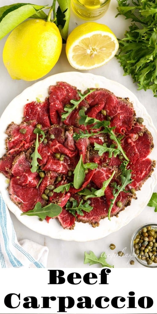 Beef Carpaccio on a plate next to capers, lemons, and arugula.