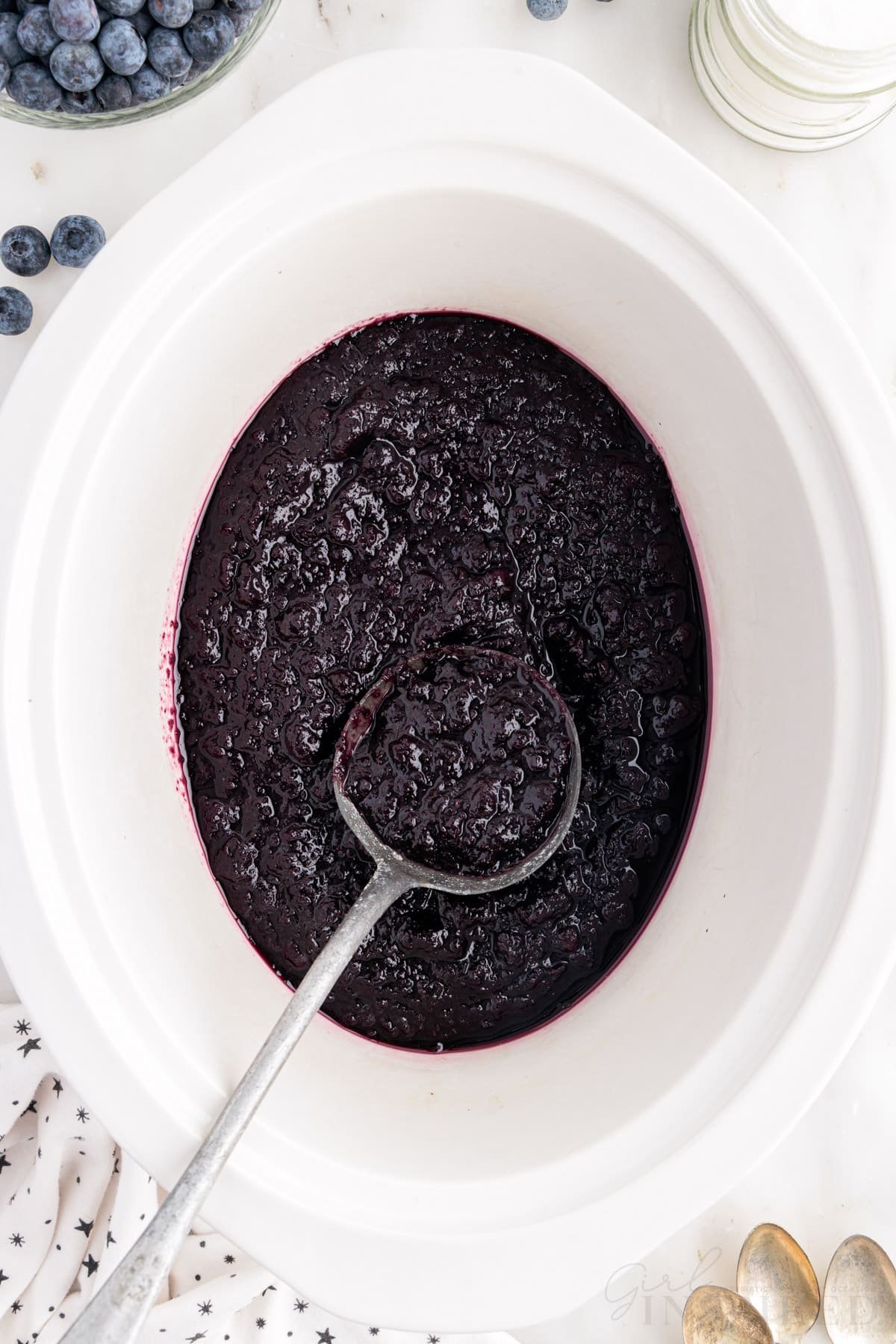 Ladle inserted in Blueberry Butter in a crockpot.