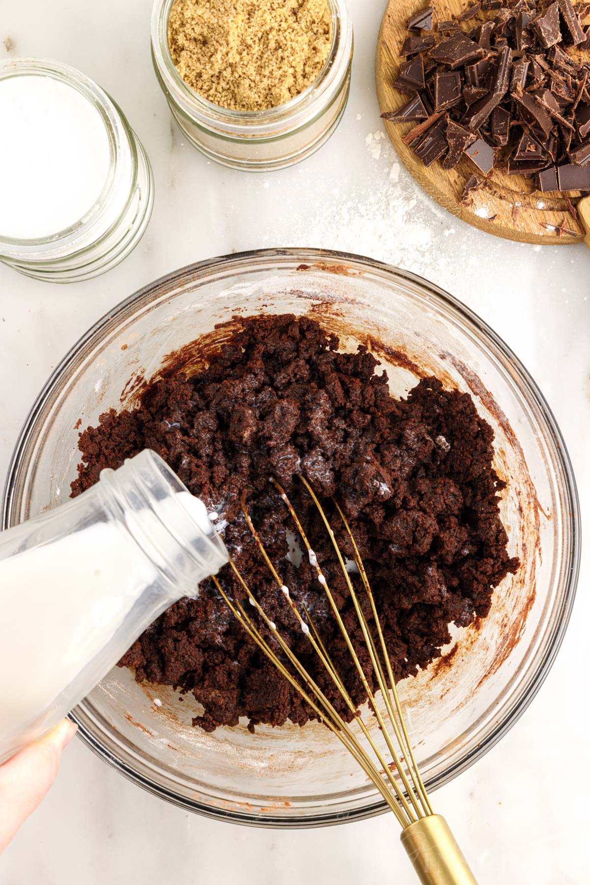 Milk added to the Edible Brownie Batter in a mixing bowl with a whisk inserted.